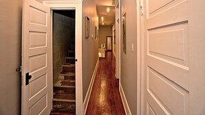 A hallway with wooden flooring, white doors, and a staircase leading to an upper level. - Downtown Savannah Oasis 4 BR 3 BA (Savannah)
