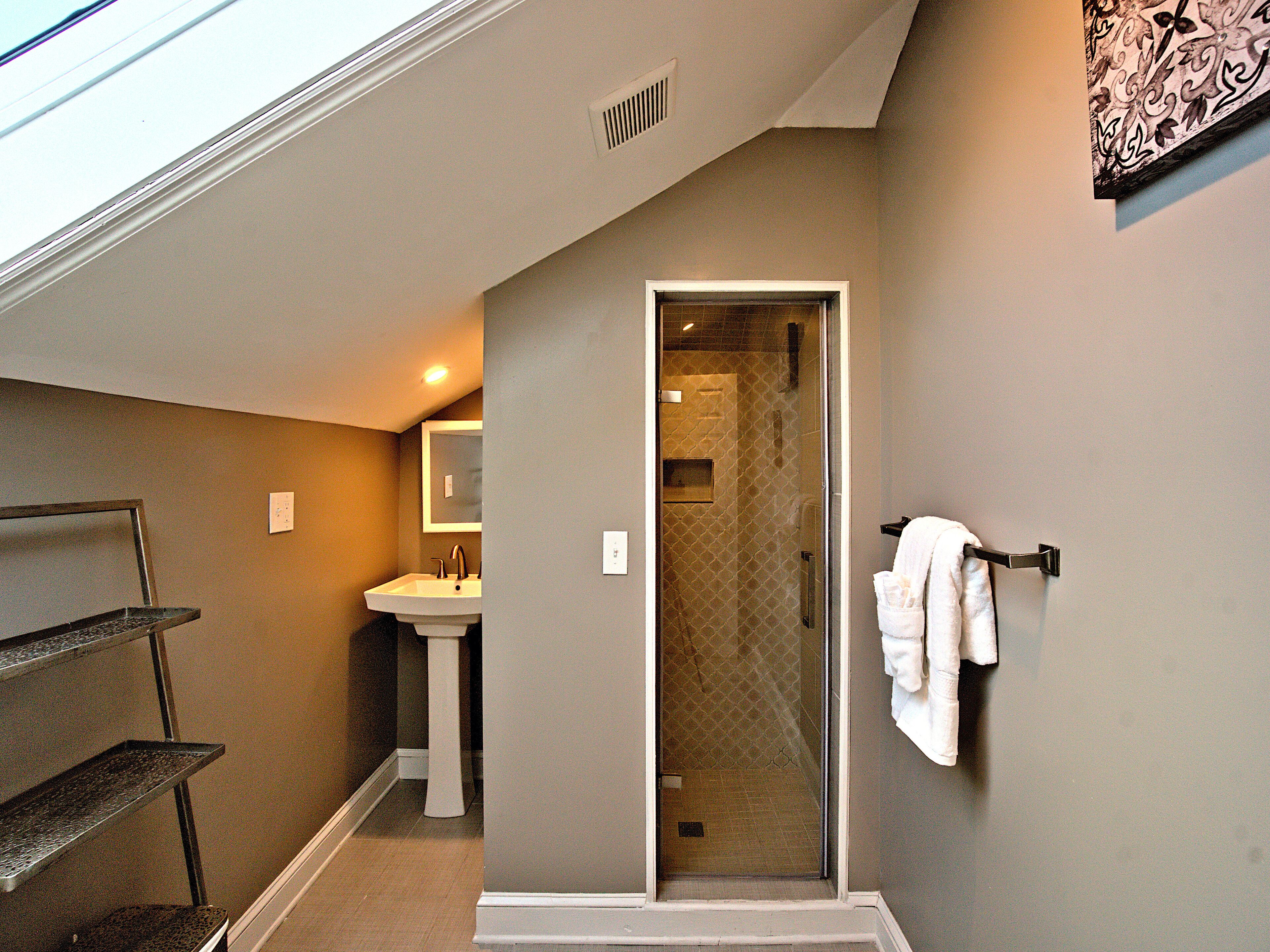 A bathroom with a sink, a glass shower door, and a towel rack.