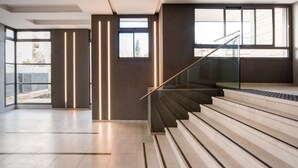 A modern interior with a staircase, large windows, and a minimalist design.