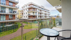A balcony with a view of a residential building complex, a grassy area, and a playground. - Apartamenty Sun&Snow Osiedle Bursztynowe (Kolobrzeg)