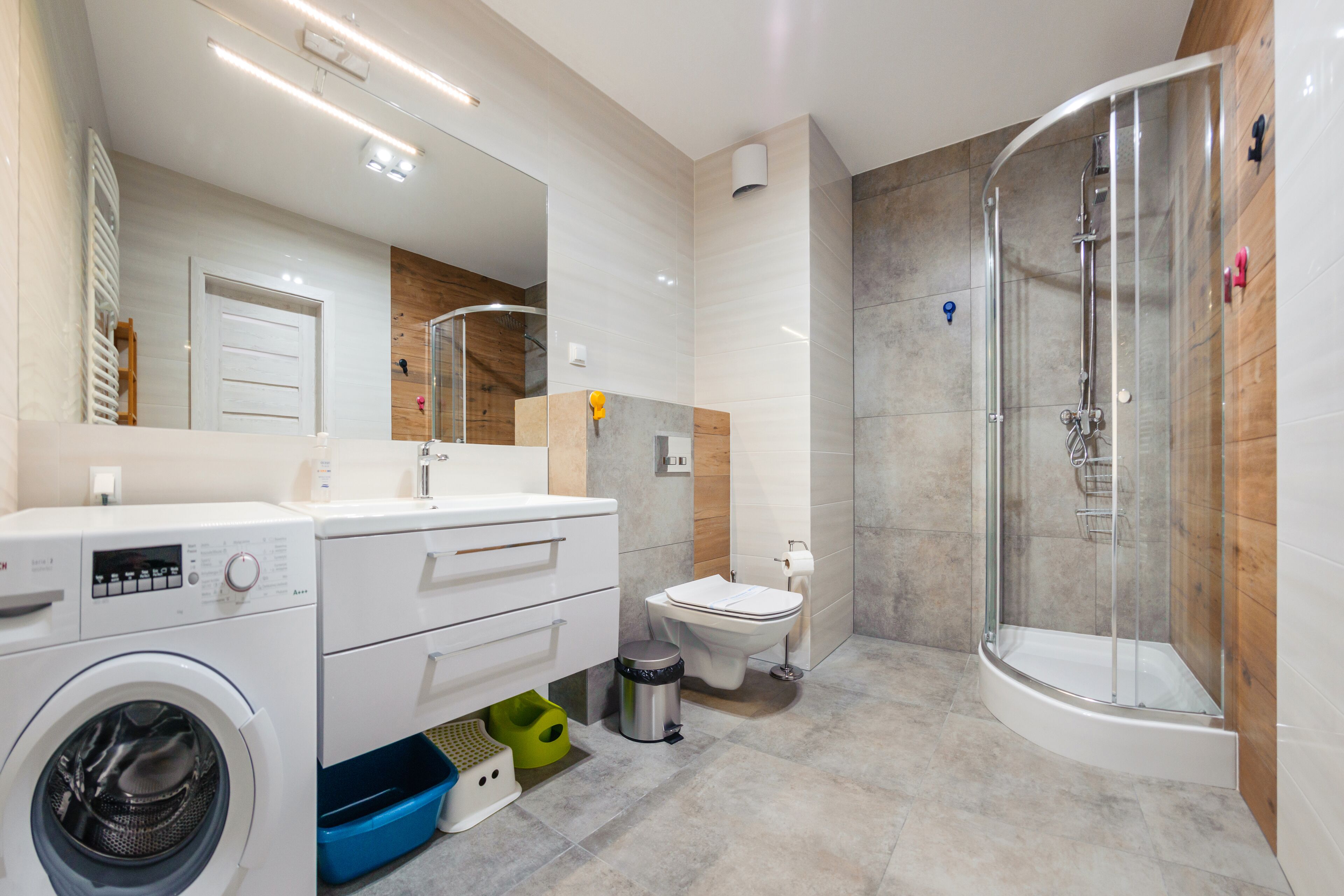 Un baño moderno con lavadora, inodoro y ducha con mampara de vidrio.