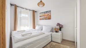 Une chambre à coucher moderne avec un grand lit, une table de chevet avec une lampe et un tableau au mur.