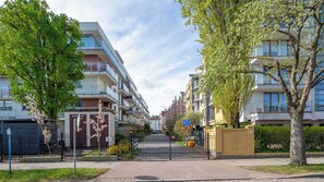 A gated residential area with modern apartment buildings, a clear sky, and a pedestrian pathway. - Apartamenty Sun&Snow Osiedle Bursztynowe (Kolobrzeg)