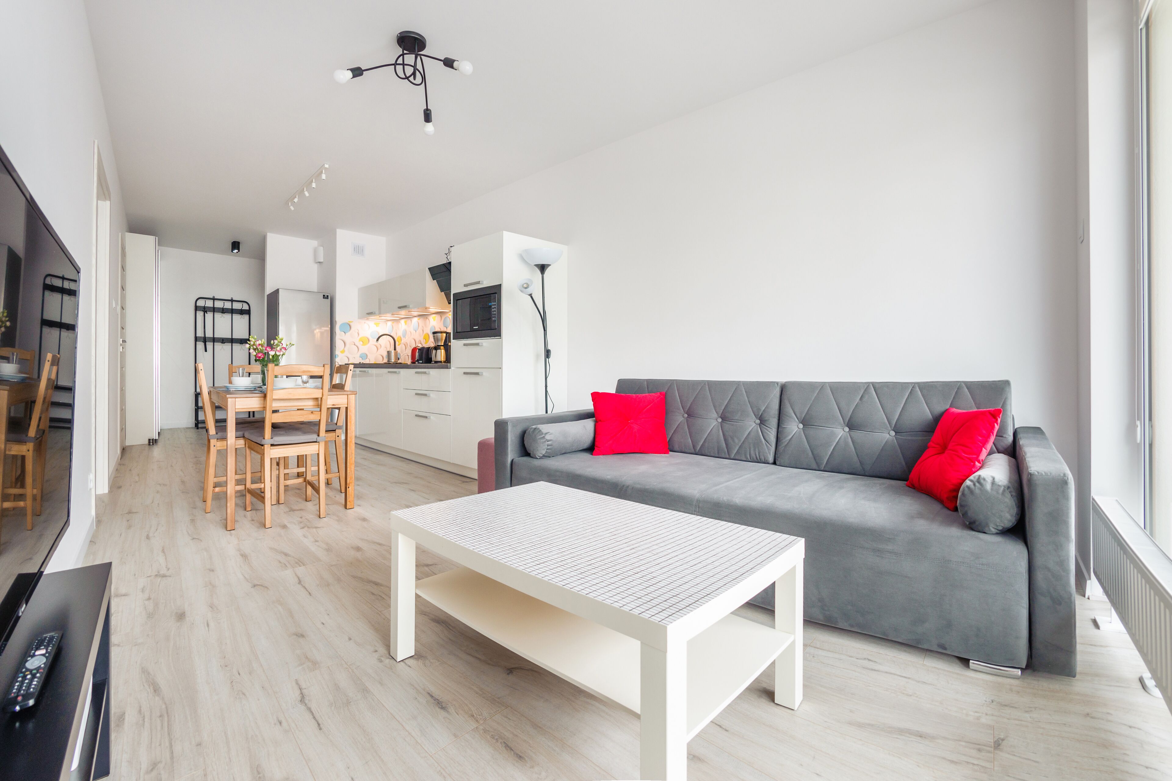 Ein modernes Wohnzimmer mit einem grauen Sofa, einem weißen Couchtisch und einem Holzessttisch.