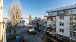 A multi-story residential building with balconies, a parking area, and a small park with trees and a playground. - Apartamenty Sun&Snow Osiedle Bursztynowe (Kolobrzeg)