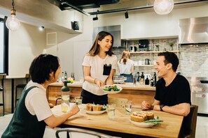 A modern kitchen with wooden countertops, stainless steel appliances, and hanging pendant lights. - GRAND HOSTEL LDK Osaka Shinsaibashi (Osaka)