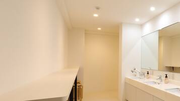 Un baño moderno con un lavamanos espacioso, un espejo grande y luces empotradas en el techo.