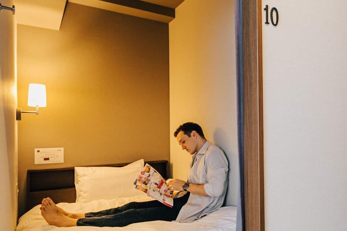 A hotel room with a bed, a nightstand, a lamp, and a door with the number 10.