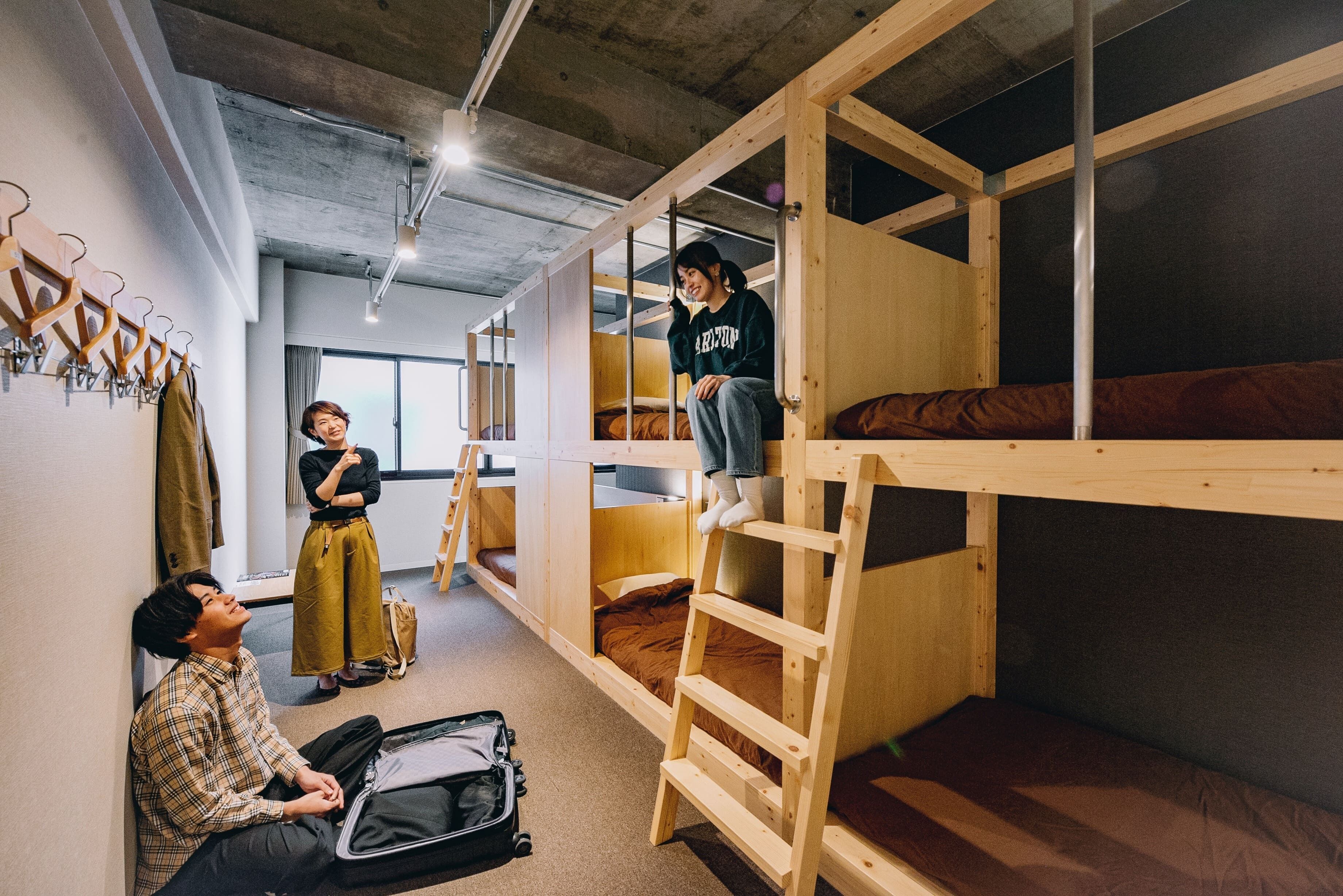 A dormitory room with bunk beds, a ladder, a desk, and a chair.