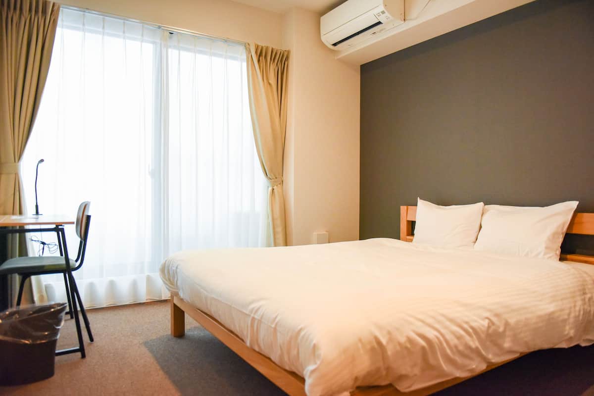 A hotel room with a bed, a desk, and a chair.
