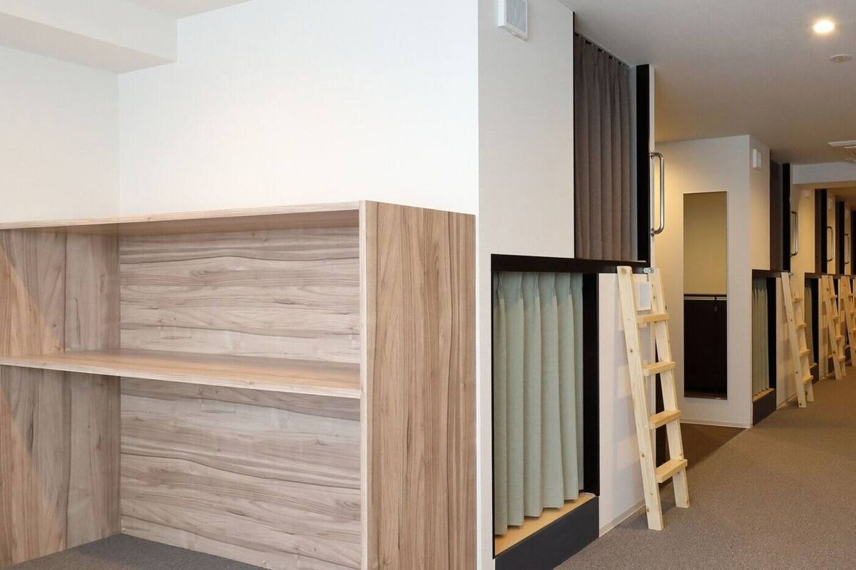 A room with bunk beds, a ladder, and a small enclosed area with curtains.
