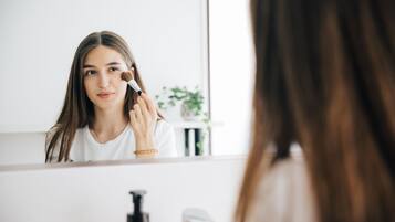 A bathroom with a mirror, a sink, and a bottle of liquid soap.