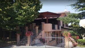 Ein zweistöckiges Haus mit einer Veranda, einem verschlossenen Eingang und einer Treppe, die zum oberen Stockwerk führt.