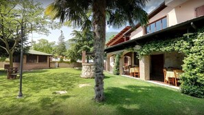 Ein modernes Haus mit Terrasse, einem Steinpfeiler und einem Essbereich mit Gartenmöbeln.