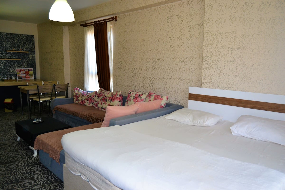 A hotel room with a large bed, a sofa, a desk, and a chair.