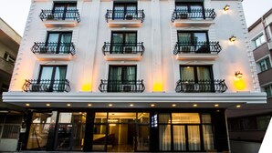 Un hôtel à plusieurs étages doté de balcons, de grandes fenêtres et d’une entrée bien éclairée.