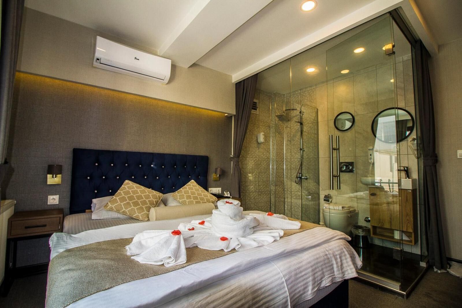 Ein Hotelzimmer mit einem großen Bett, einer Glaskabinedusche und einer Wandmontage-Klimaanlage.