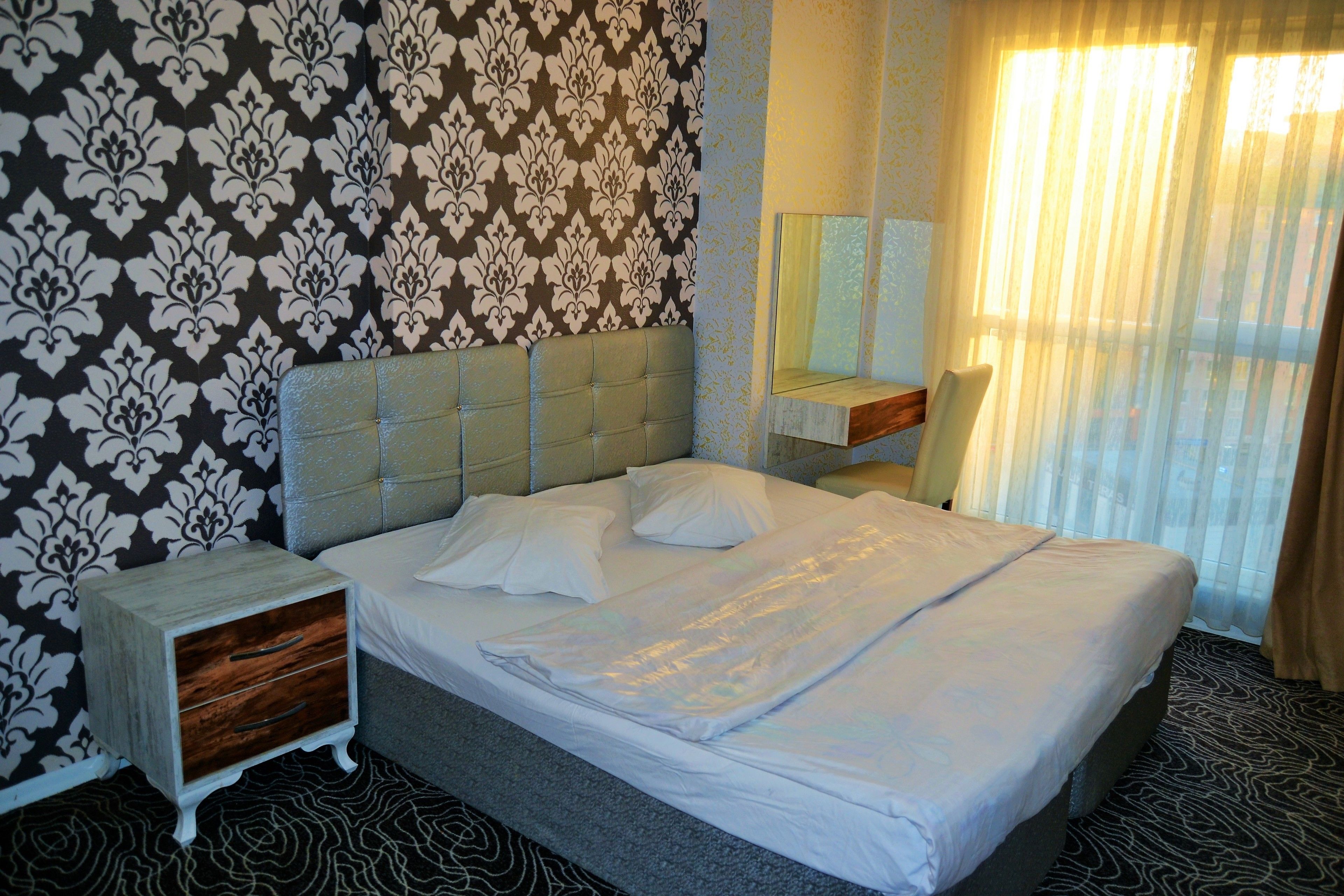 Ein Hotelzimmer mit Bett, Nachttisch, Spiegel und einer Wand mit Muster.