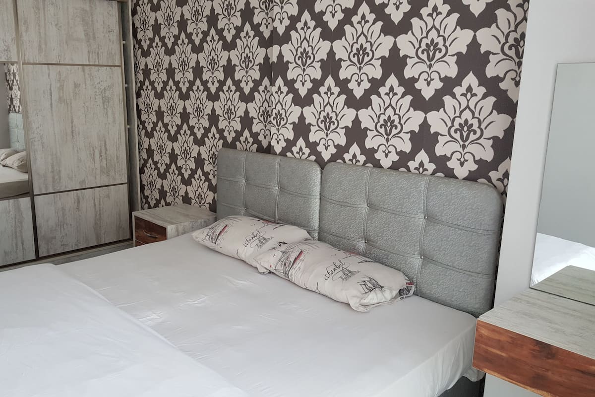 A bedroom with a bed, a nightstand, a dresser, and a mirror.