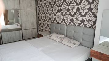 A bedroom with a bed, a nightstand, a dresser, and a mirror.