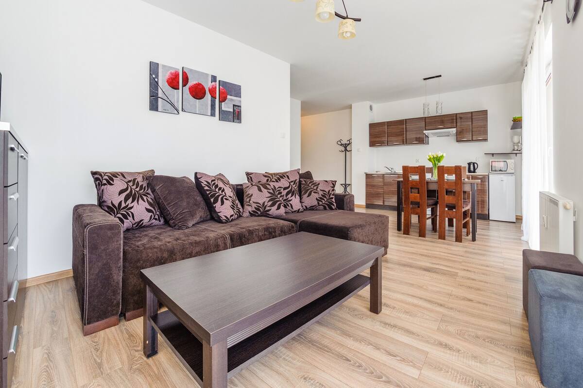 Ein modernes Wohnzimmer mit Sofa, Couchtisch und einem Essbereich mit Stühlen und Tisch.
