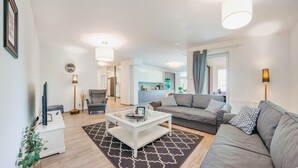 A modern living room with a sofa, coffee table, and a dining area visible in the background. - Apartamenty Sun & Snow Polanki (Kolobrzeg)