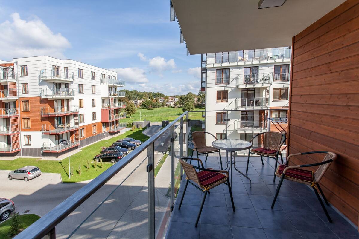 Ein Balkon mit Tisch und Stühlen, mit Blick auf eine Straße und Wohnhäuser.