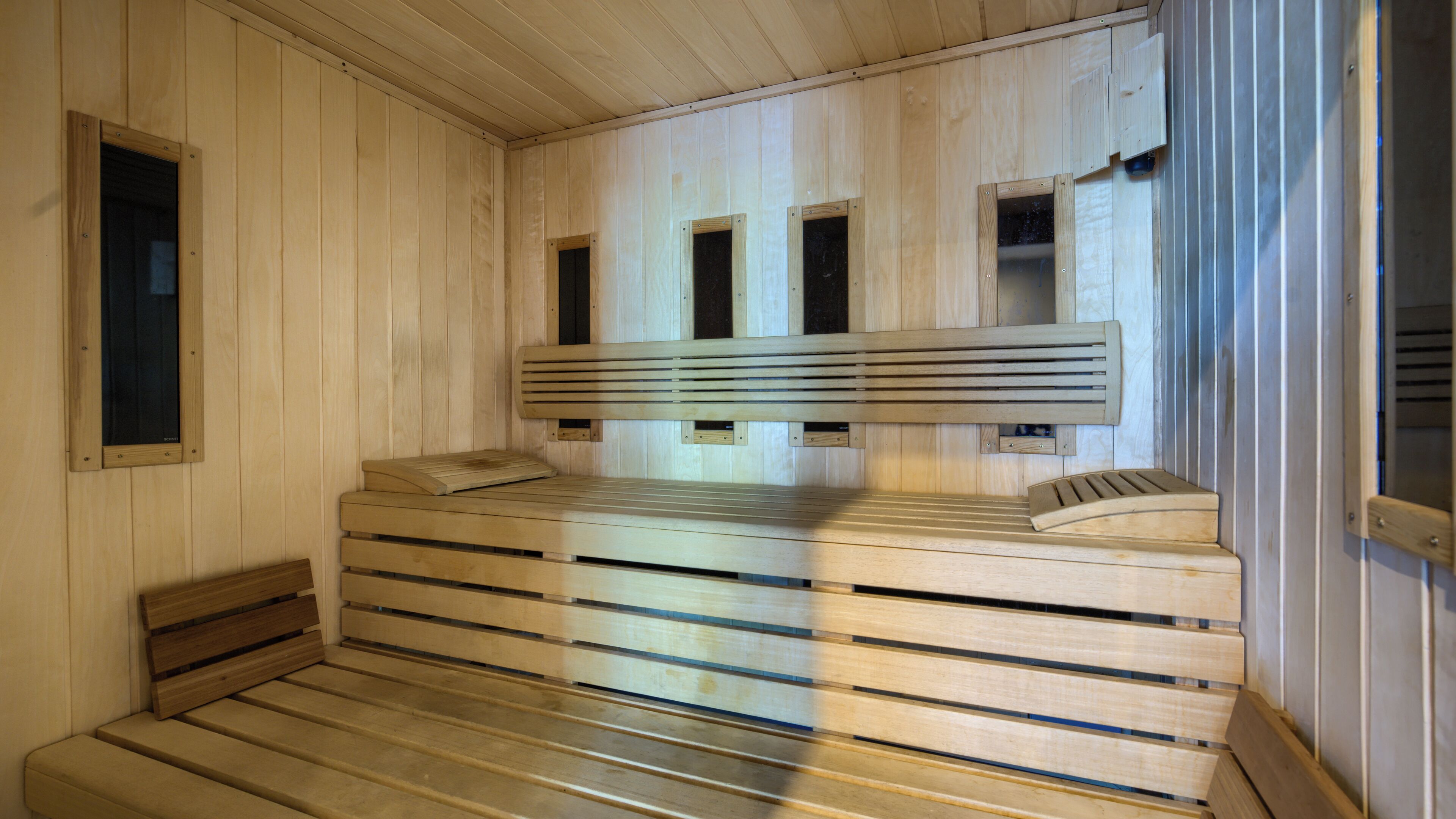 Una sauna con bancos de madera y techo de listones.