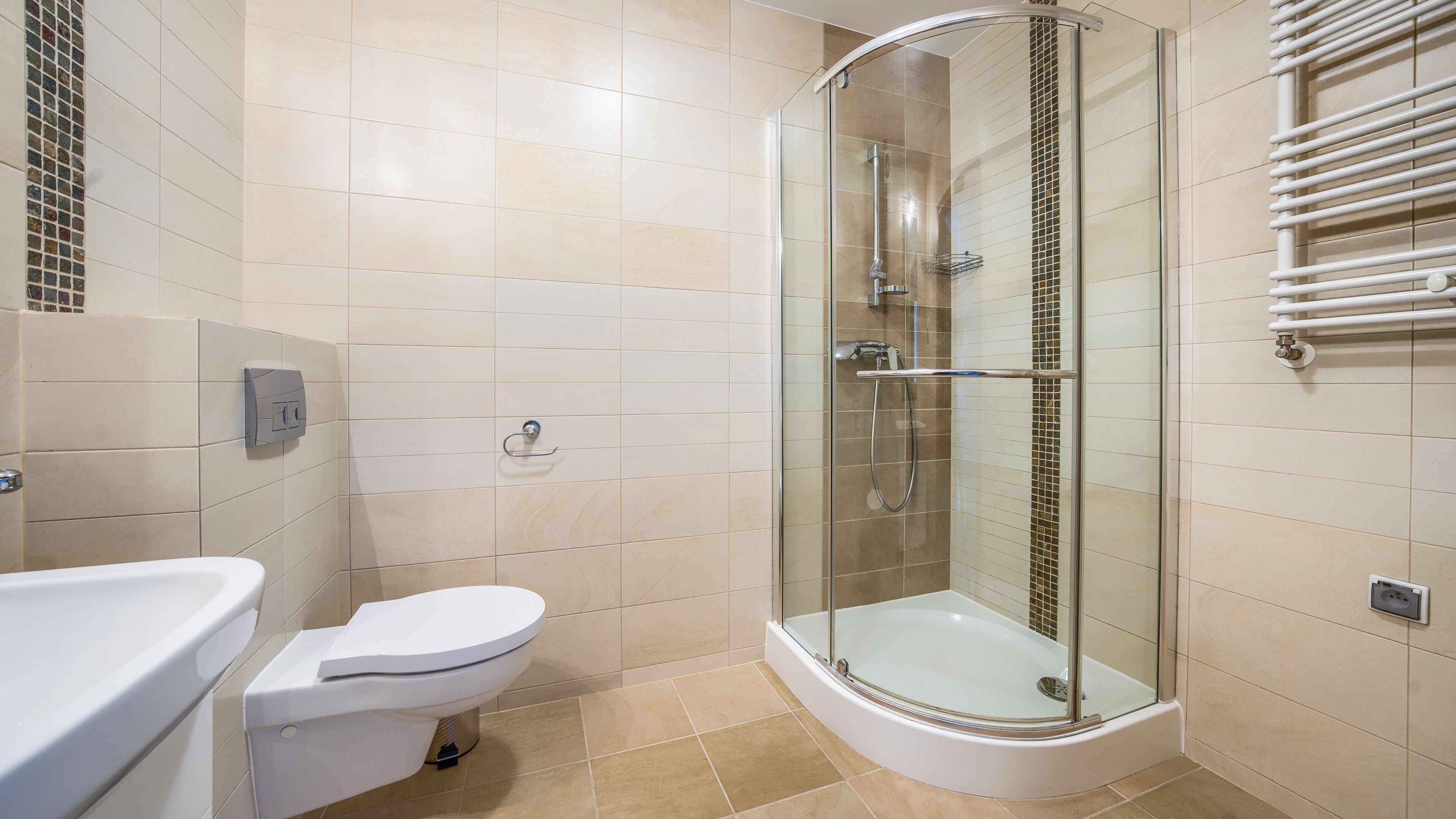 Une salle de bain moderne dotée d’une douche à parois de verre, de toilettes et d’un lavabo.