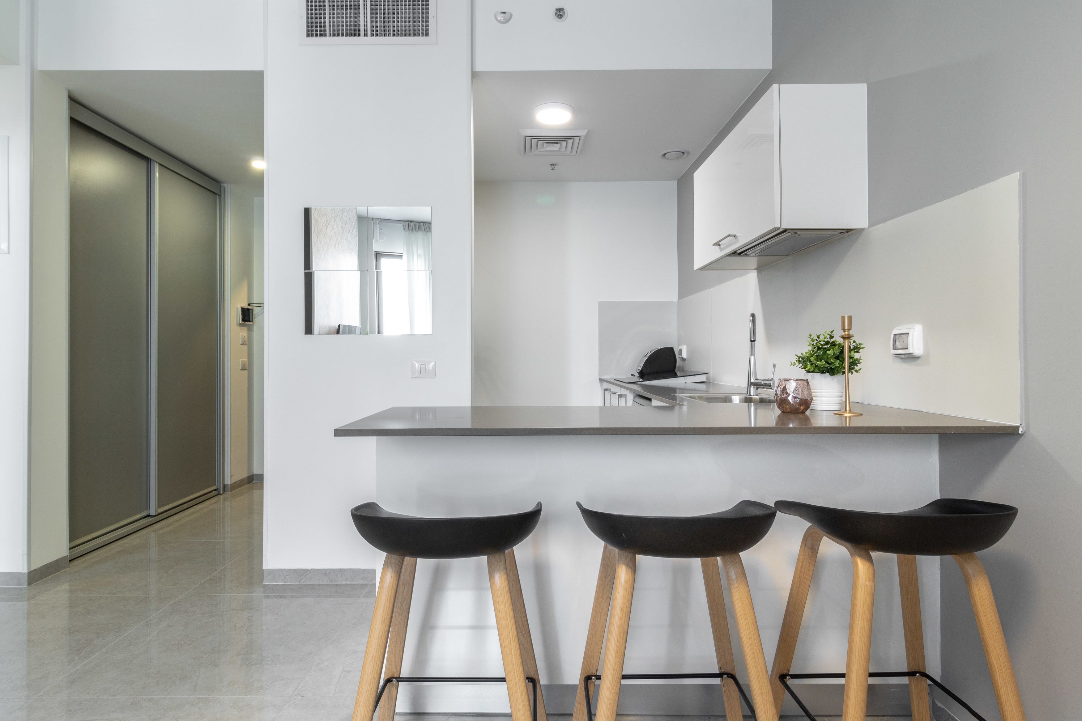A modern kitchen with a central island, bar stools, and a view of the adjacent living area.