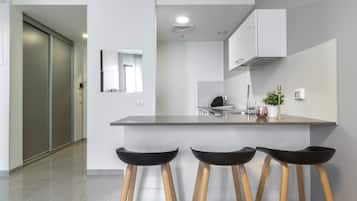 A modern kitchen with a central island, bar stools, and a view of the adjacent living area.