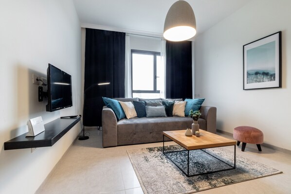 Una sala de estar moderna con un sofá, una mesa de centro, un televisor y una lámpara colgante.