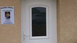 A white door with a small window above it, flanked by two blue flower planters. - Les Collinades de Chalons (Fagnieres)