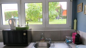 A kitchen with a microwave, sink, and windows overlooking a garden. - Les Collinades de Chalons (Fagnieres)