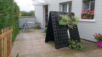 A patio with a table and chairs, a wooden fence, and potted plants.
