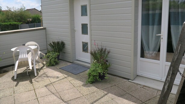 A patio with a white door, a small table with chairs, and potted plants. - Les Collinades de Chalons (Fagnieres)