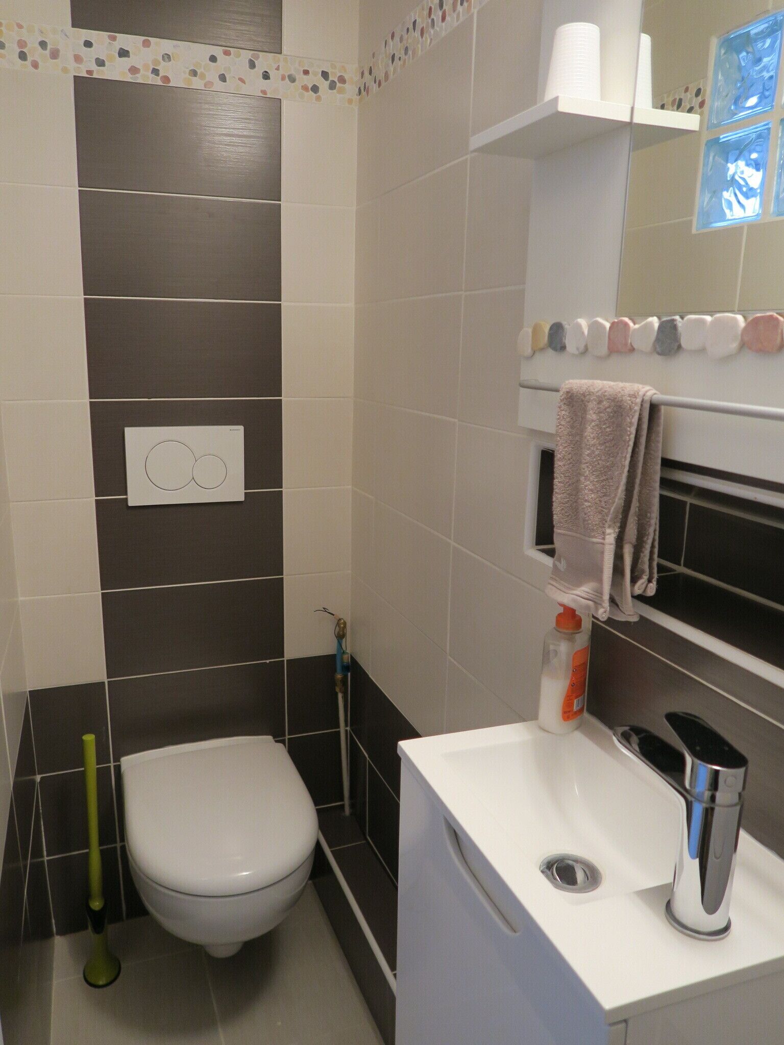 A bathroom with a toilet, a sink, a towel rack, and a shower.