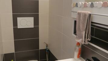A bathroom with a toilet, a sink, a towel rack, and a shower.