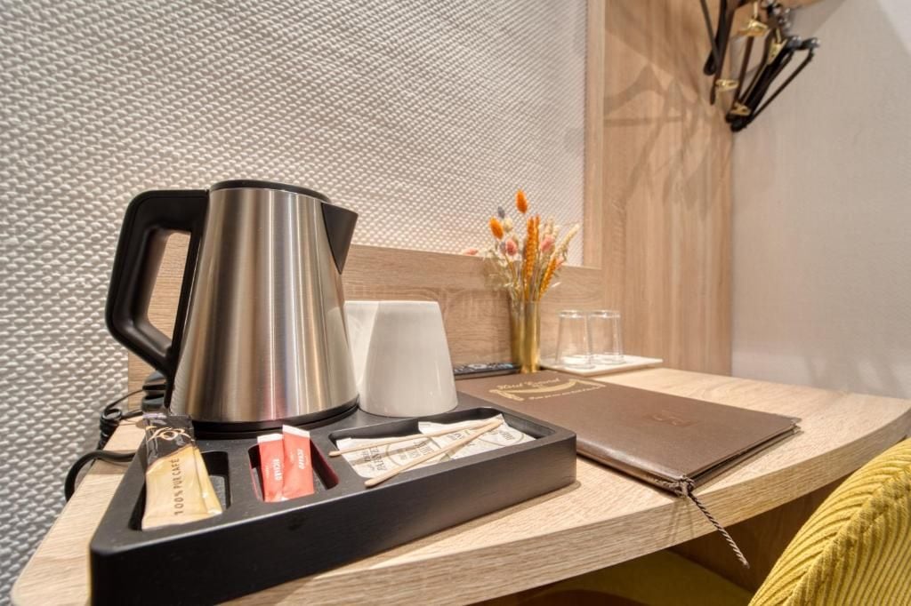 Una kitchenette con cafetera, bandeja con cubiertos, vaso y un florero con flores secas.