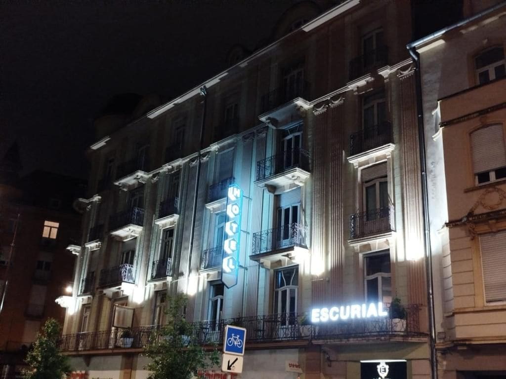 A building with a sign that reads 'ESCURIAL' and a blue bicycle rental sign.