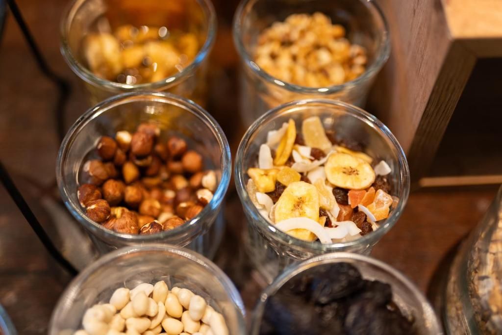 Verschiedene Lebensmittel in Glasbehältern, darunter Nüsse, Trockenfrüchte und möglicherweise Granola.
