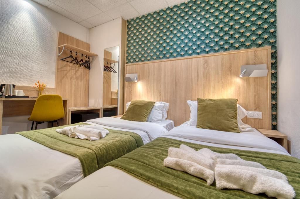 Habitación de hotel con dos camas, un escritorio, una silla y un espejo.
