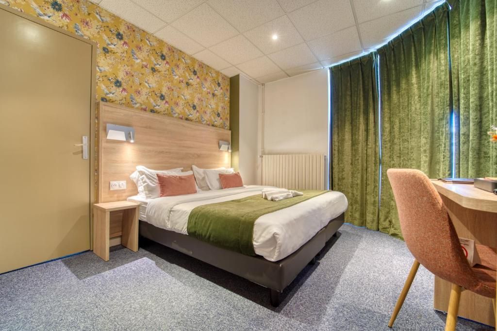 Ein Hotelzimmer mit Bett, Nachttisch, Sessel und Schreibtisch mit Stuhl.