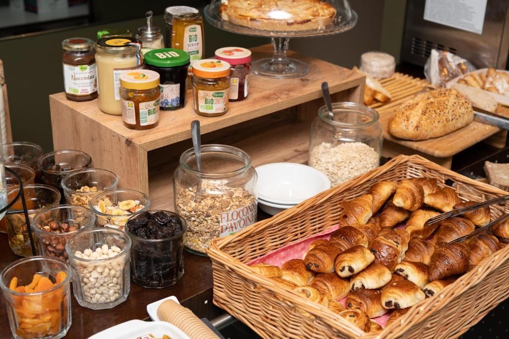 A buffet table with various food items, including jars of spreads, a basket of croissants, and a display of bread.