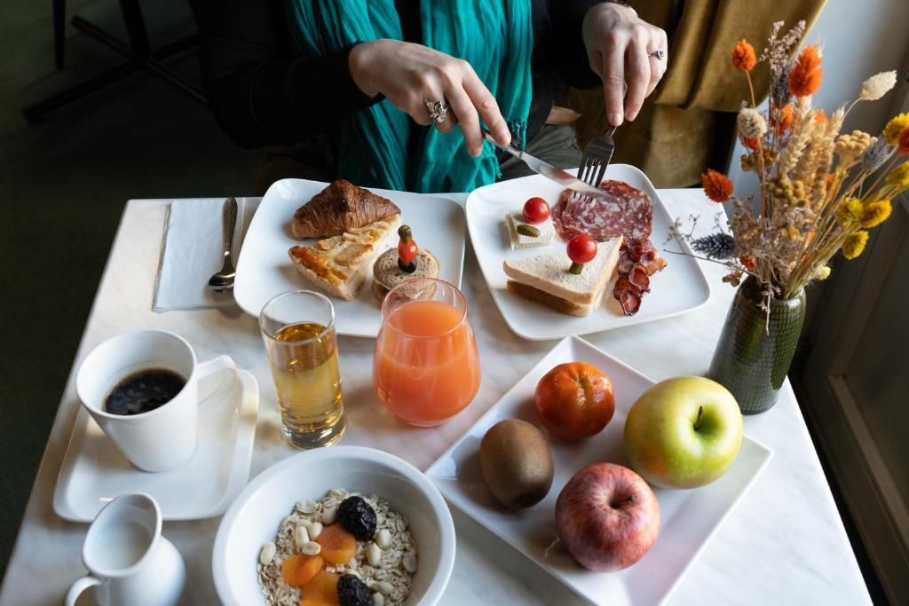 Een ontbijttafel met diverse soorten eten, drinken en een vaas met gedroogde bloemen.