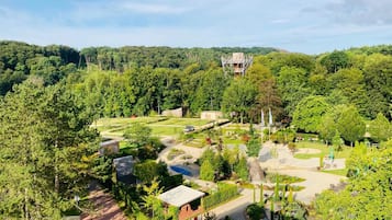 Um jardim com paisagismo, caminhos, um pequeno edifício e uma estrutura distante.