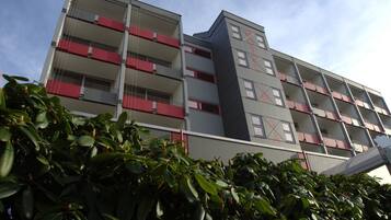 Un hotel de varios pisos con balcones, un diseño arquitectónico moderno y un cielo despejado.
