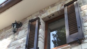 A stone building with two windows featuring wooden shutters. - B&B Lavanda e Rosmarino (Assisi)