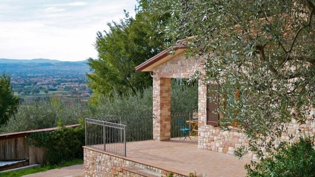A stone-built villa with a patio, a metal railing, and a view of the countryside. - B&B Lavanda e Rosmarino (Assisi)