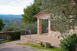 A stone-built villa with a patio, a metal railing, and a view of the countryside. - B&B Lavanda e Rosmarino (Assisi)